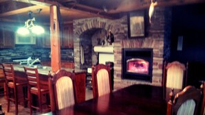 Un comedor con una mesa y sillas de madera, una chimenea de piedra y una lámpara colgante.