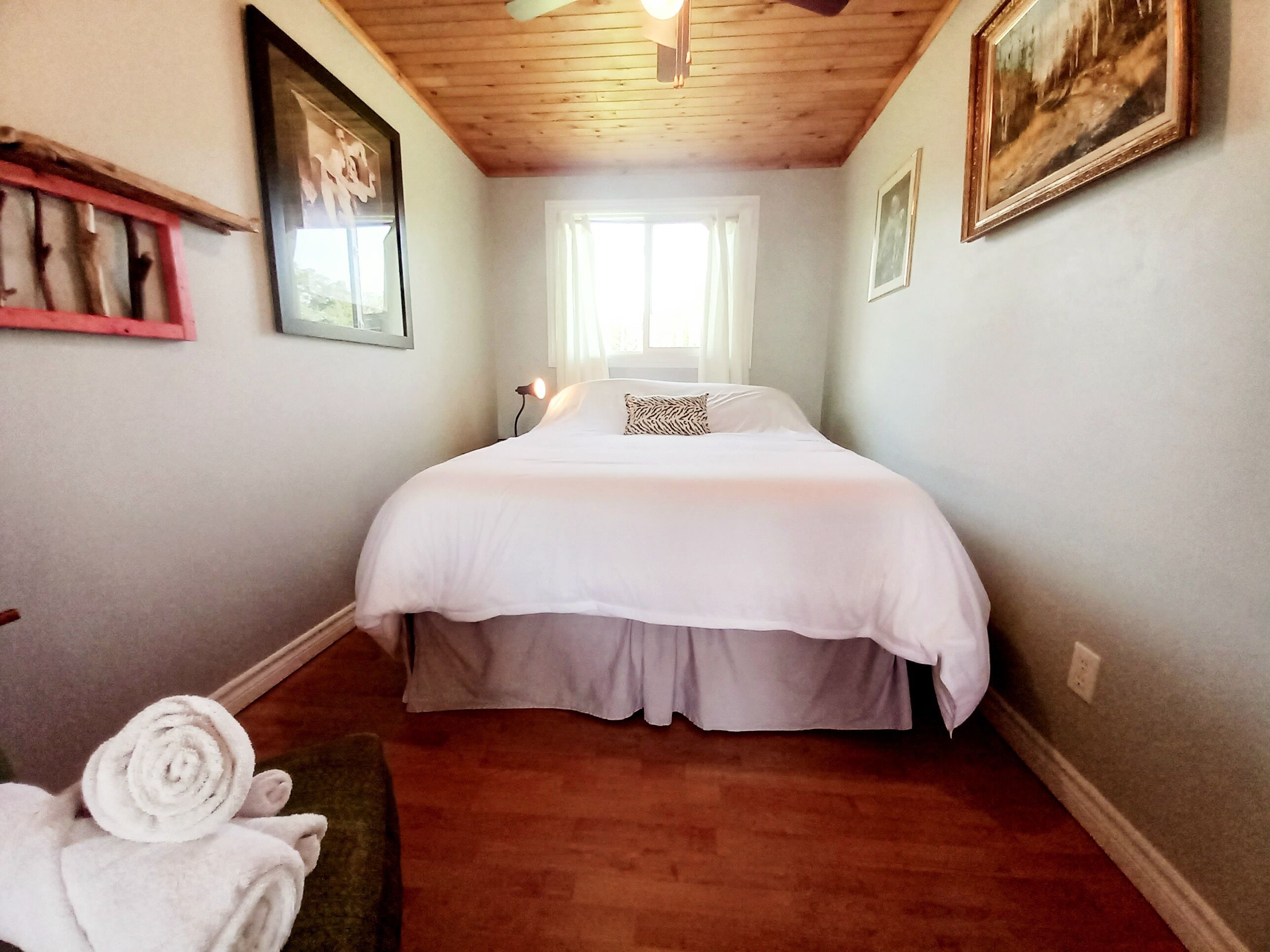 Une chambre à coucher avec un lit, une fenêtre et un plafond en bois.