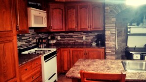 Una cocina con gabinetes de madera, microondas, estufa y encimera de granito.