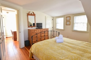 A bedroom with a bed, a dresser, a television, and a window.