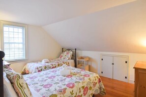 Een slaapkamer met twee bedden, een raam, een kledingkast en een nachtkastje.