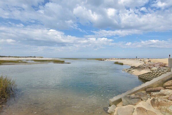 Un paysage côtier avec une étendue d’eau calme, une côte rocheuse et un ciel dégagé.