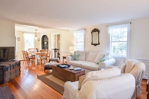 A living room with a sofa, coffee table, and a dining area with chairs and a table.