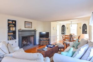 Un salon avec une cheminée, un téléviseur et un coin repas comprenant des chaises et une table.