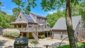 Uma casa de dois andares com varanda coberta, garagem e painéis solares no telhado.