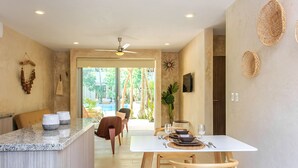 A modern kitchen with a marble countertop, wooden chairs, and a dining table set for two. - Charming Nature-Inspired Condos with Sultry Surroundings by Stella Rentals (Tulum)