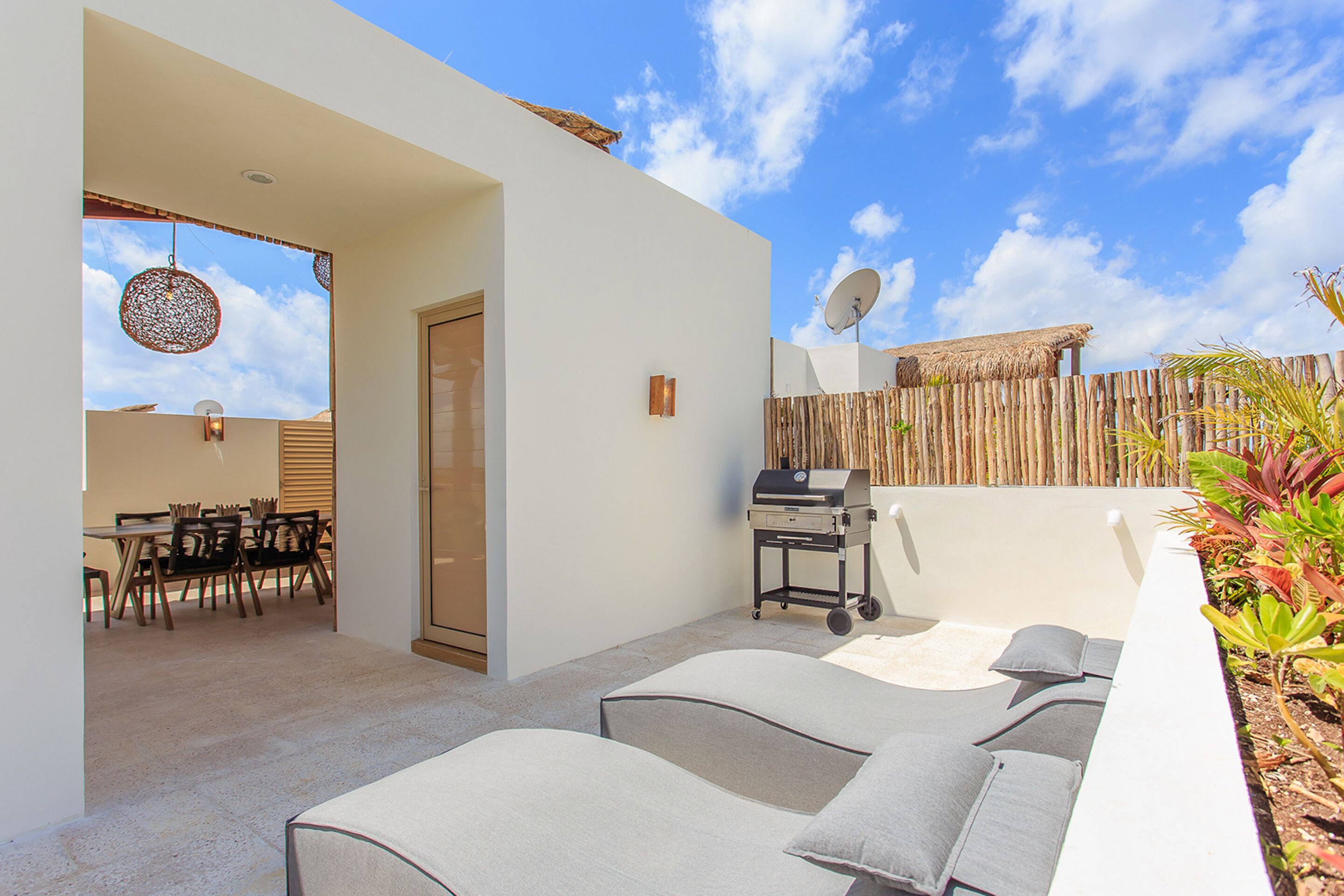 A modern outdoor patio with lounge chairs, a grill, and a dining area.