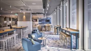 A modern restaurant with high tables, bar stools, and blue sofas.