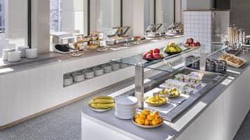 A buffet area with various food items and dishes, including fruits, pastries, and beverages.