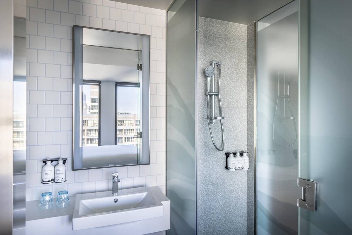 A modern bathroom with a white sink, a large mirror, and a glass-enclosed shower area.