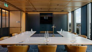 Une salle de conférence dotée d’une longue table, de chaises et offrant une vue sur la ville grâce à de grandes fenêtres.