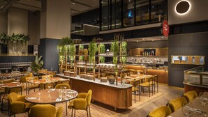 A modern restaurant with multiple dining areas, a central bar, and vertical gardens. - voco Auckland City Centre by IHG (Auckland)