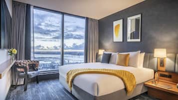 Une chambre d’hôtel avec un grand lit, un bureau et une vue sur le paysage urbain par la fenêtre.