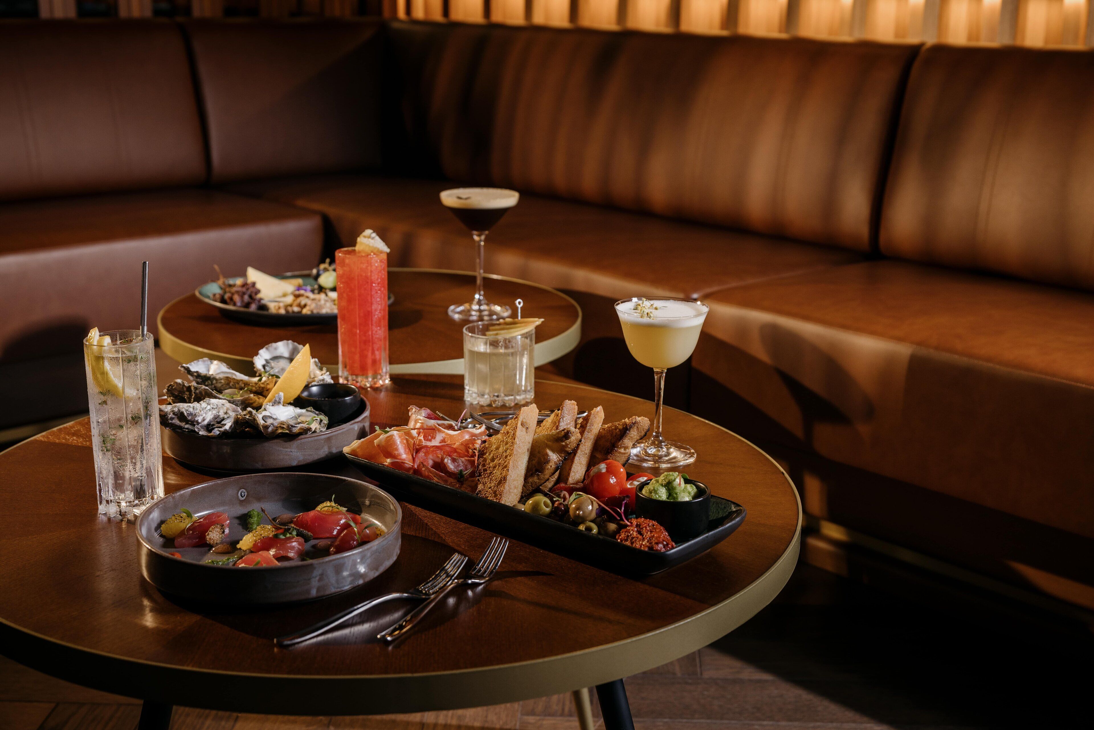 Mesa de comedor dispuesta con diferentes platos, bebidas y un vaso de agua.