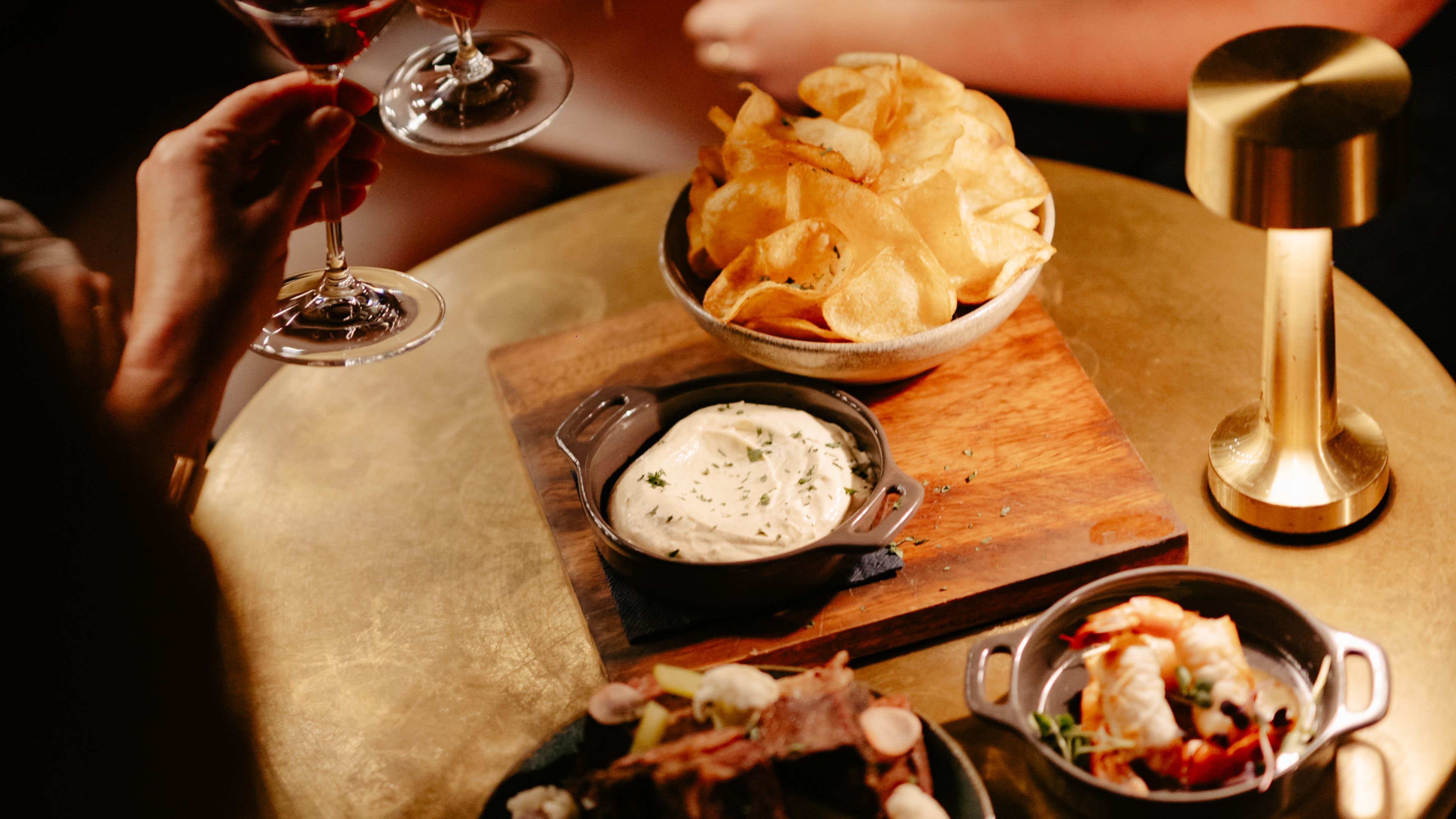 Een eettafel met een schaal chips, een bakje dipsaus en een schotel met zeevruchten.
