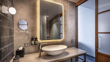 A modern bathroom with a large mirror, a round mirror, a vessel sink, and a towel rack.
