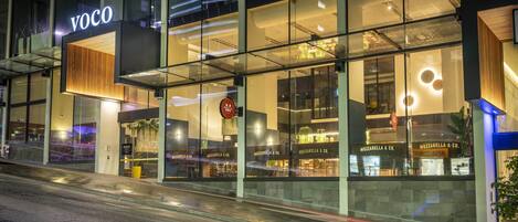Un edificio moderno con fachada de vidrio y señalización que dice 'VOCO'.