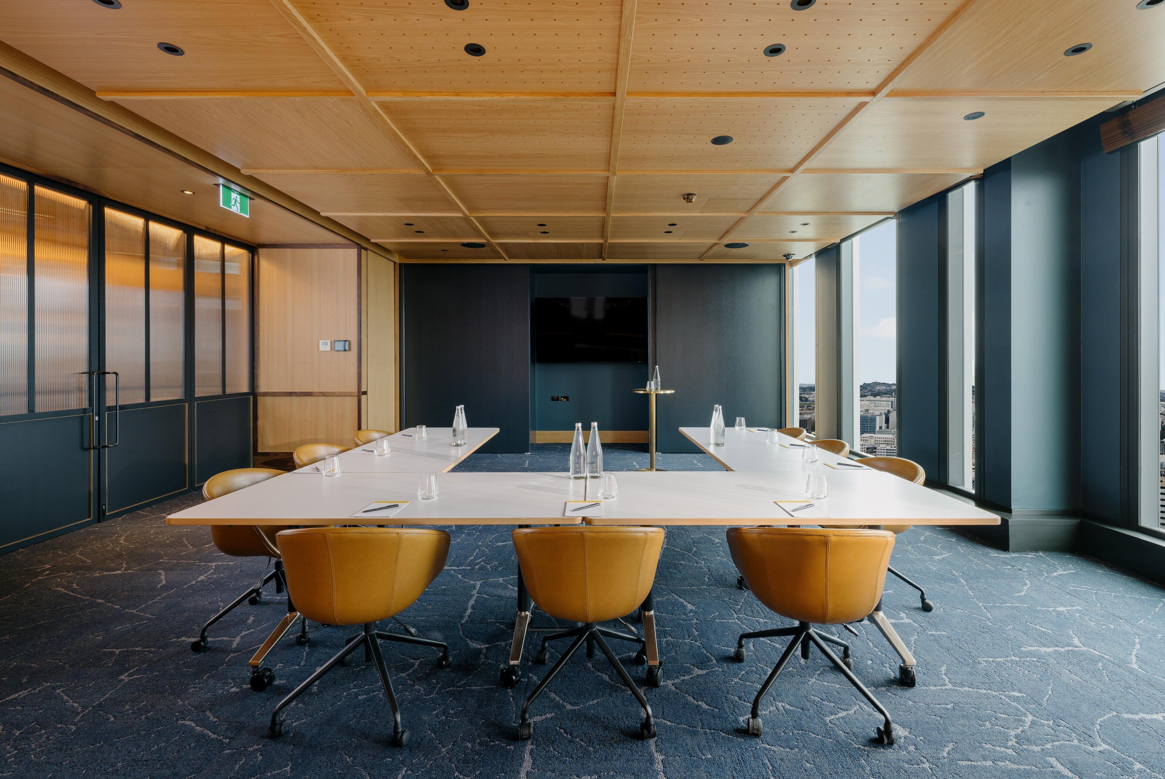 A conference room with a long table, yellow chairs, and large windows offering a view of the city.