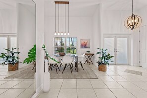 Un espace de salle à manger moderne avec une table centrale, des chaises et des luminaires suspendus.