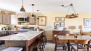 Una cocina moderna con una isla grande, luces colgantes y un candelabro.