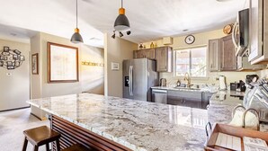 Una cocina moderna con una isla de mármol, electrodomésticos de acero inoxidable e iluminación colgante.