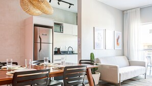 Un salon moderne comprenant un canapé, une table à manger, des chaises, un coin cuisine et une plante en pot.