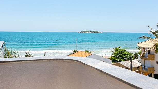 Une vue côtière avec une plage, l’océan et une petite île au loin.