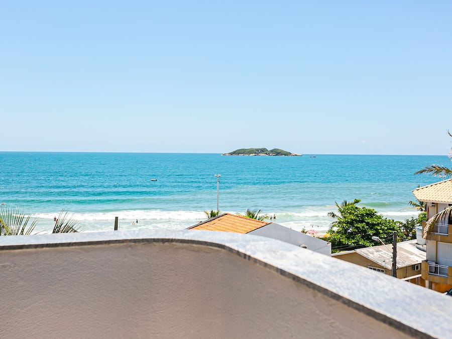 Vista costera con playa, océano y una pequeña isla en la distancia.