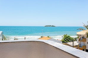 Vista costera con playa, océano y una pequeña isla en la distancia.