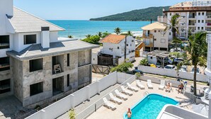 Un espace piscine avec des chaises longues, une piscine et une vue sur la mer.