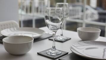 Un tavolo da pranzo con un bicchiere di vino, ciotole e piatti.