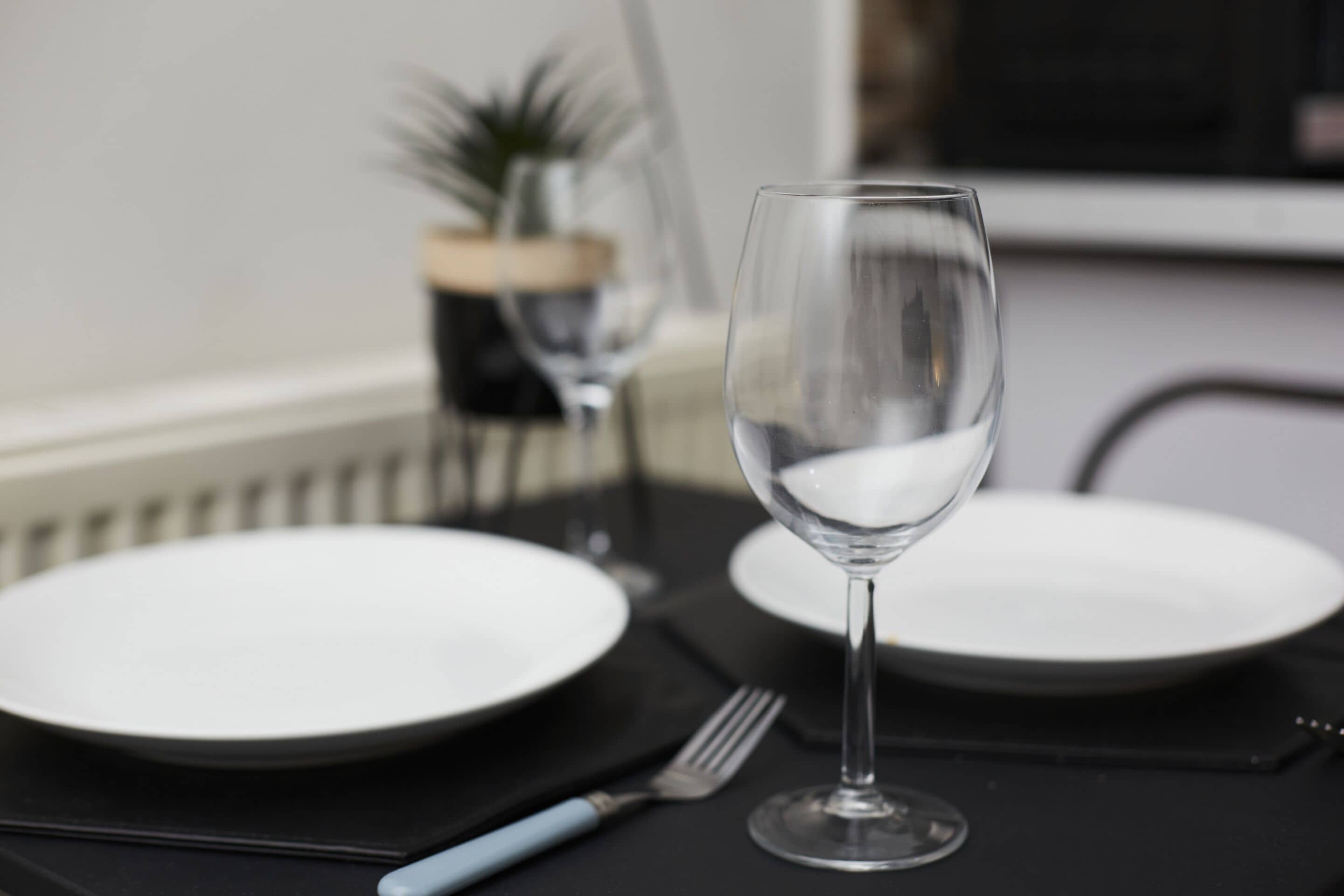 Une table à manger avec un verre à vin, deux assiettes et une fourchette.