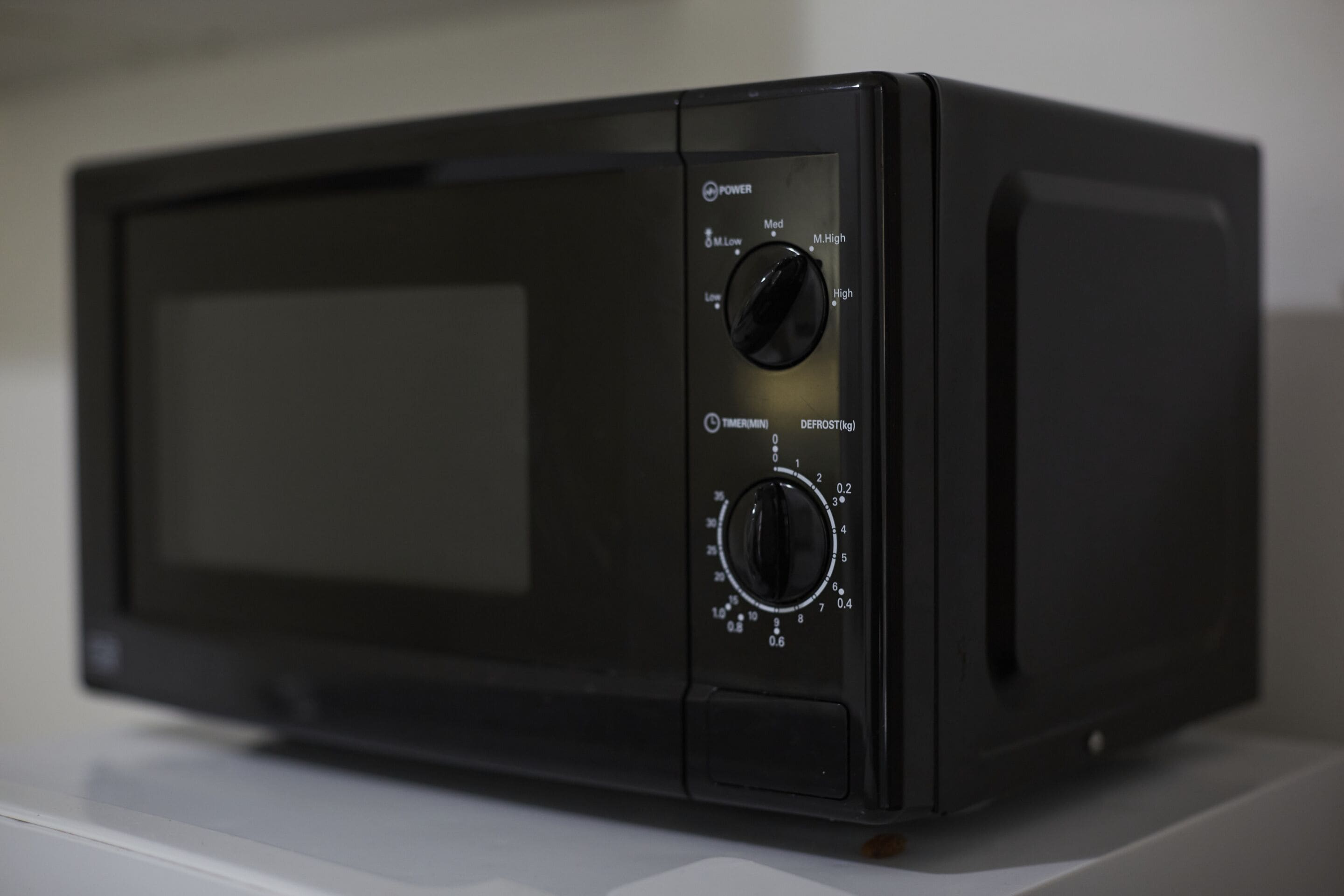 A black microwave with a digital display, power settings, timer, and defrost controls.