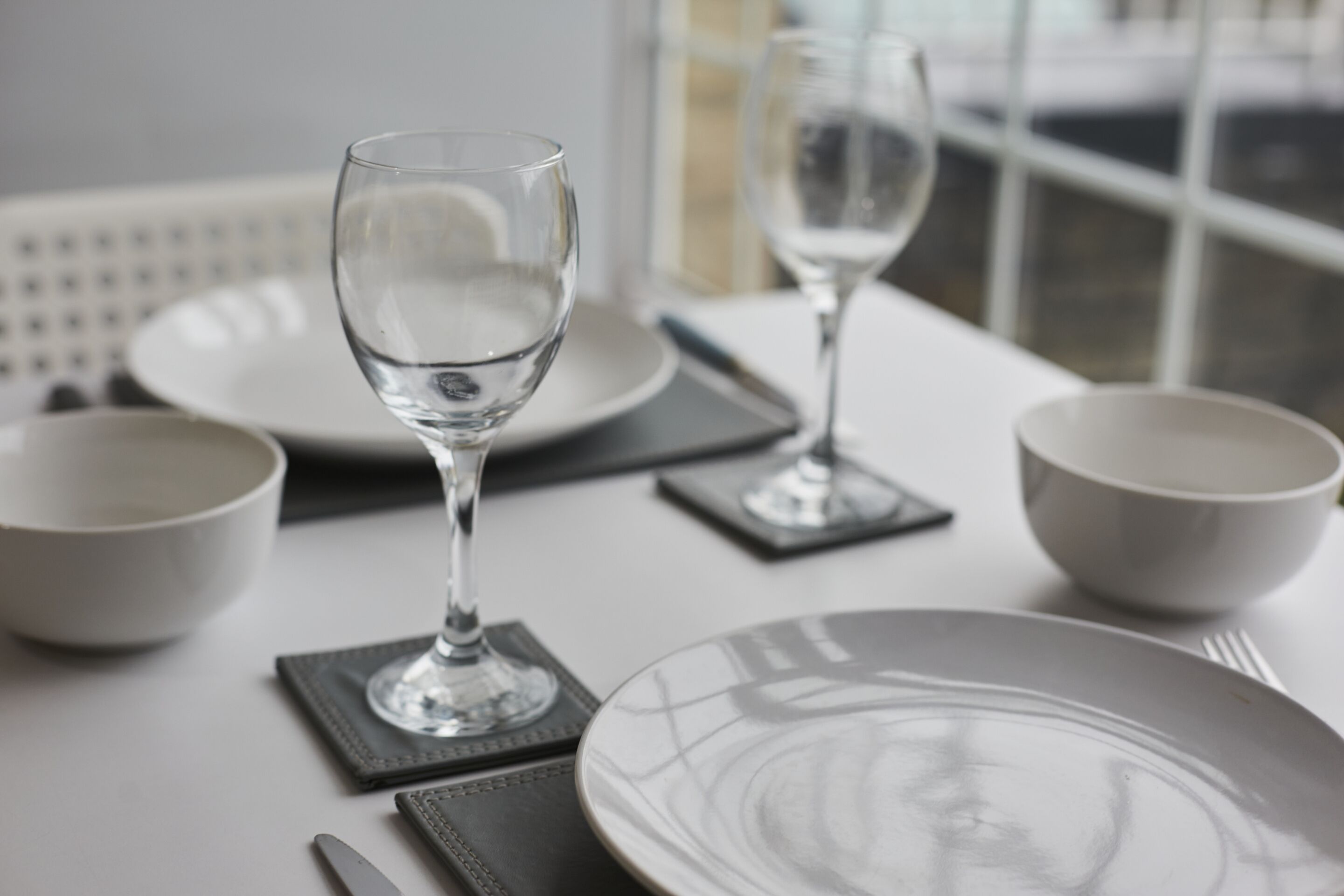 A table set with white plates, clear glasses, and a knife.