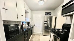 A compact kitchen with a toaster oven, a refrigerator, a stove, and a microwave. - 3-bedroom vacation home 12 minutes from Paycom Center (Midwest City)
