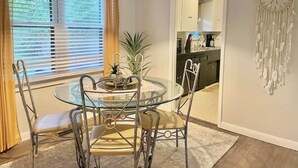 A dining area with a glass table and metal chairs, a pendant light, a dreamcatcher on the wall, and a view into the kitchen. - 3-bedroom vacation home 12 minutes from Paycom Center (Midwest City)