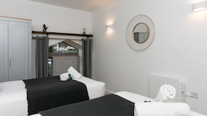 A hotel room with two beds, a wardrobe, a mirror, and a radiator. - Strawberry Line, Flat 1 (Wells)