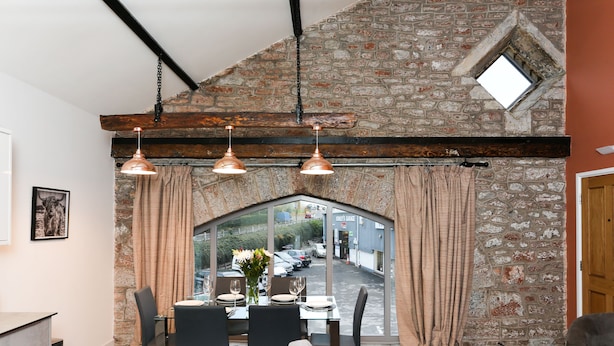 A dining area with a stone wall, wooden beams, and a view of the street. - Strawberry Line, Flat 1 (Wells)