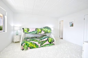 A bedroom with a bunk bed, a bedside table with a lamp, and a framed picture on the wall.