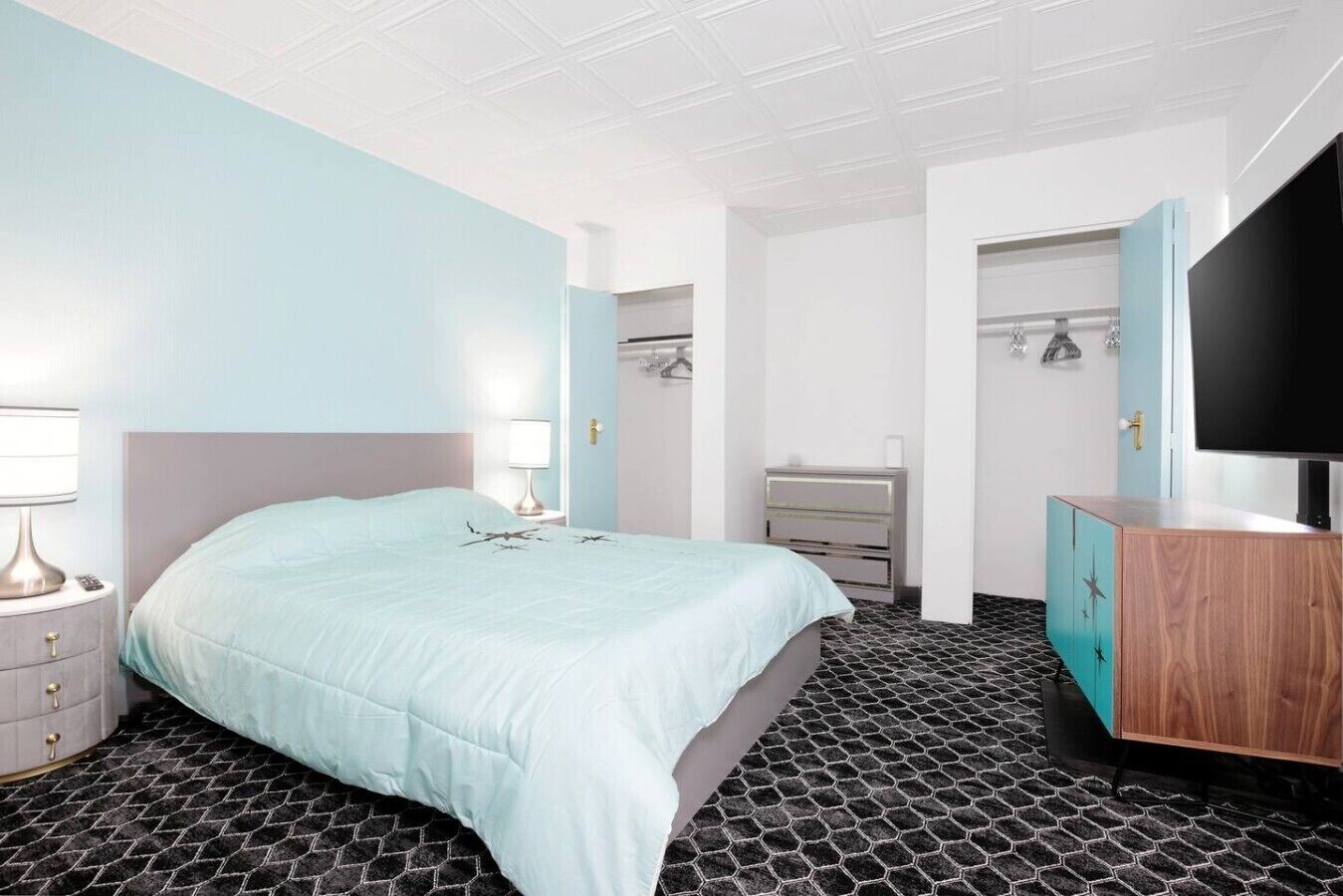 Habitación de hotel con cama, cómoda, televisor y baño visible a través de una puerta abierta.