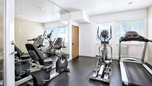 A gym with cardio machines, a mirrored wall, and large windows. - Retro Condo Extreme High End finishings (Scottsdale)
