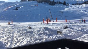 A ski slope with a clear sky, snow-covered ground, and a mountain in the background. - STUDIO CABIN 4PERS ESXPOSE SUD PIED PISTE (la plagne villages)