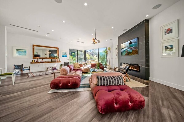A modern living room with a fireplace, plush red sofas, and a large mirror.