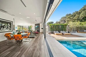 A modern interior with a dining area, a pool, and a view of the outdoors.
