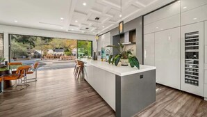 A modern kitchen with a central island, wooden flooring, and a view of the outdoors.