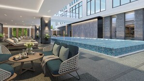 Un área de piscina interior moderna con asientos y vistas al cielo.