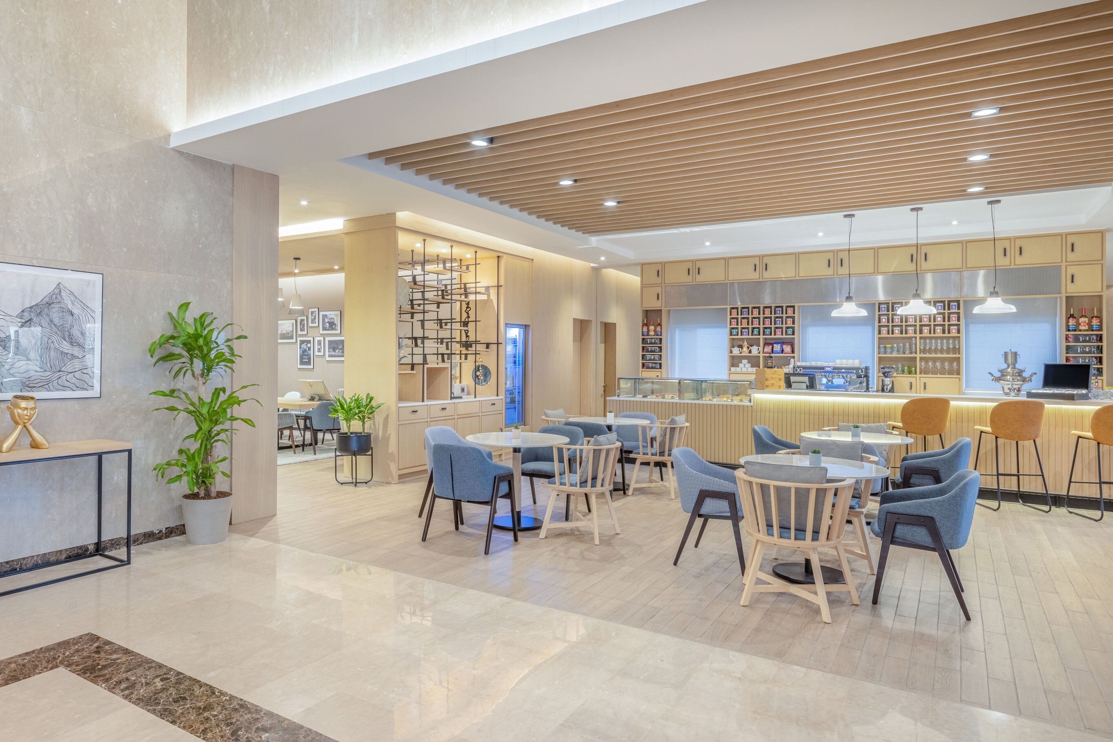 Un interior moderno con una zona de bar, asientos y una exhibición de libros y objetos decorativos.