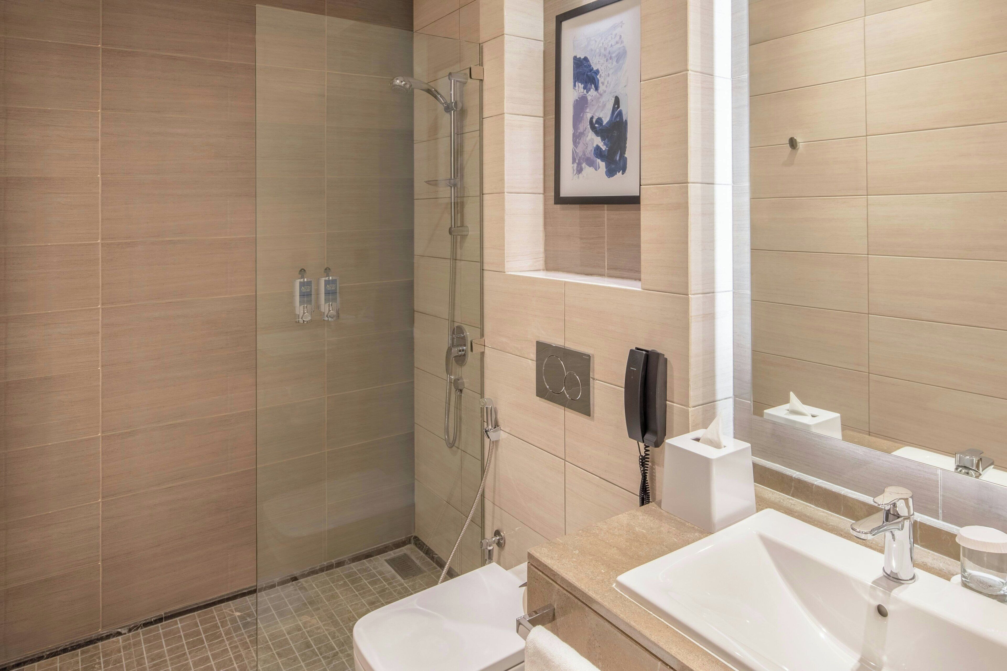 Un baño moderno con ducha de vidrio, lavamanos blanco y espejo.