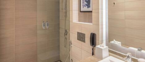 Un baño moderno con ducha de vidrio, lavamanos blanco y espejo.