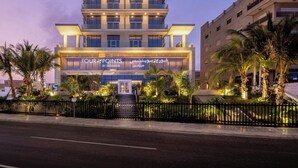 Un hotel alto con varios balcones, una entrada bien iluminada y un letrero que dice "FOUR POINTS BY SHERATON".
